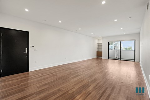 a living room with white walls and wood floors and a sliding glass door