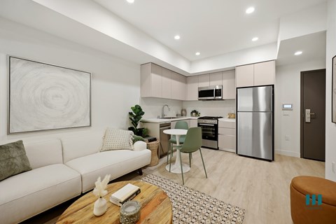 A modern kitchen with a dining table and chairs, a couch, and a painting on the wall.