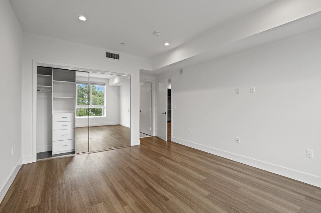 Bedroom with Mirrored Closet with Built-In Shelving, Recessed Lighting, and Vinyl Flooring