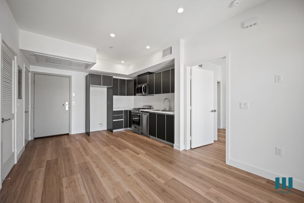 A kitchen with white cabinets and a wooden floor.