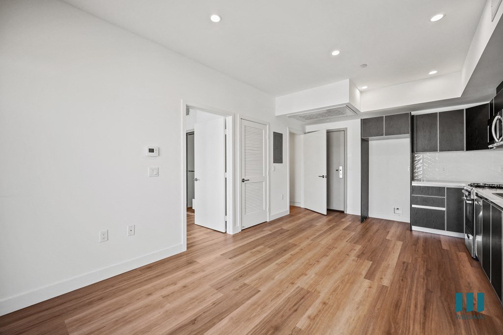 A kitchen area with white cabinets and a wooden floor.