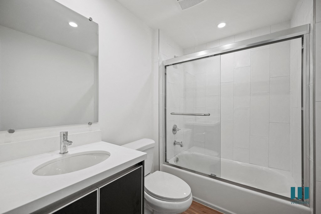 A white bathroom with a sink, toilet, and shower.