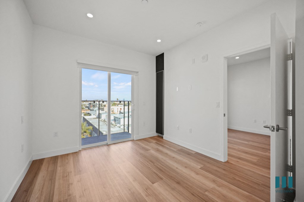 A room with a wooden floor and a large window overlooking a cityscape.