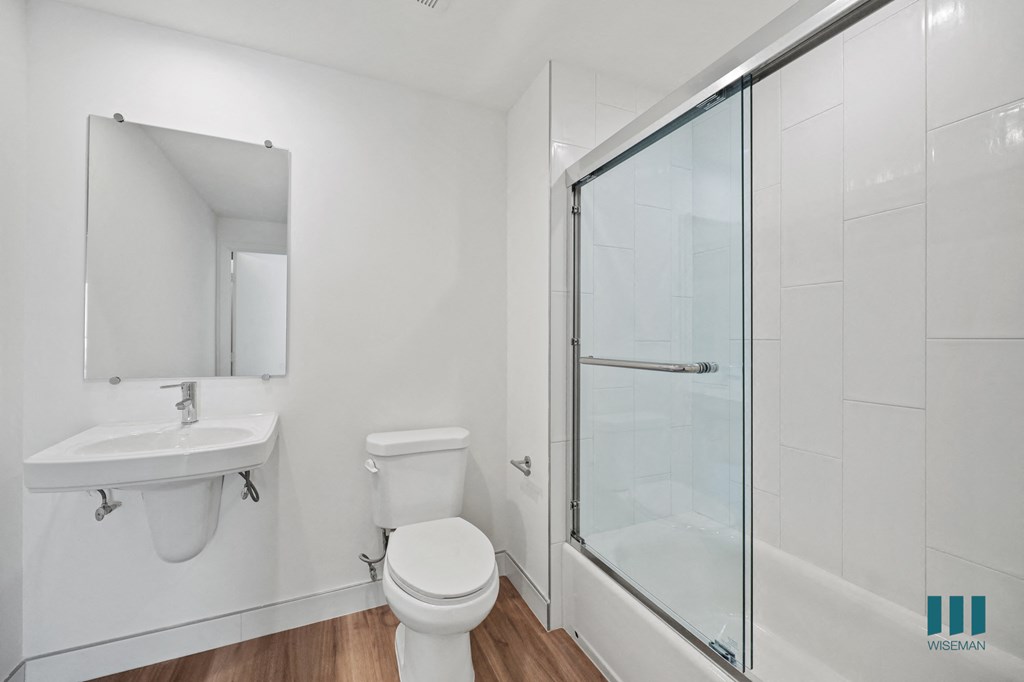 A white bathroom with a toilet, sink, and shower.