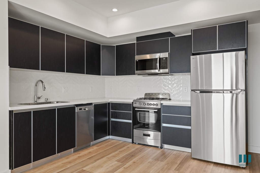 A modern kitchen with stainless steel appliances and black cabinets.