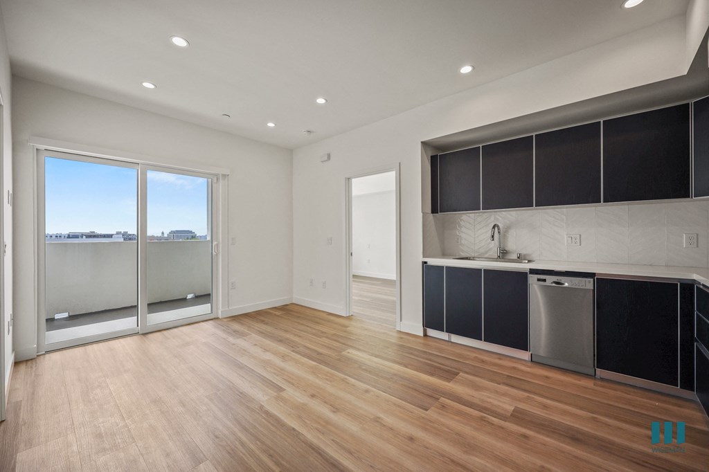 A modern kitchen with a wooden floor and a large window.