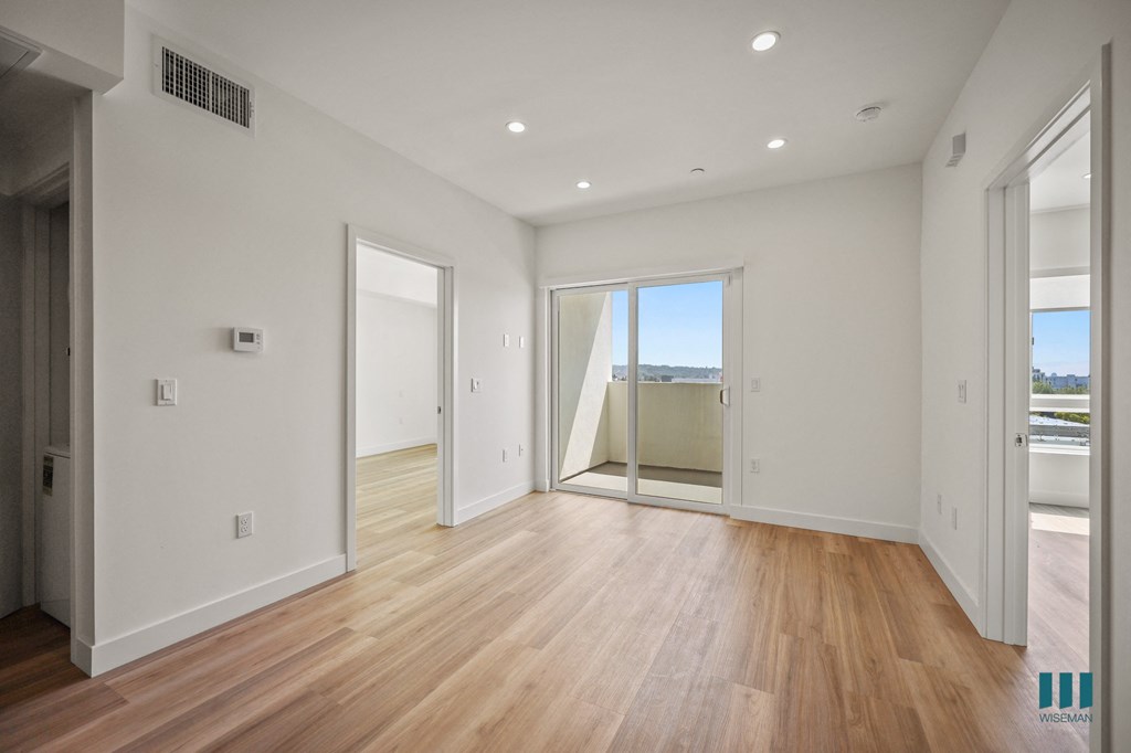 A spacious room with wooden floors and white walls.