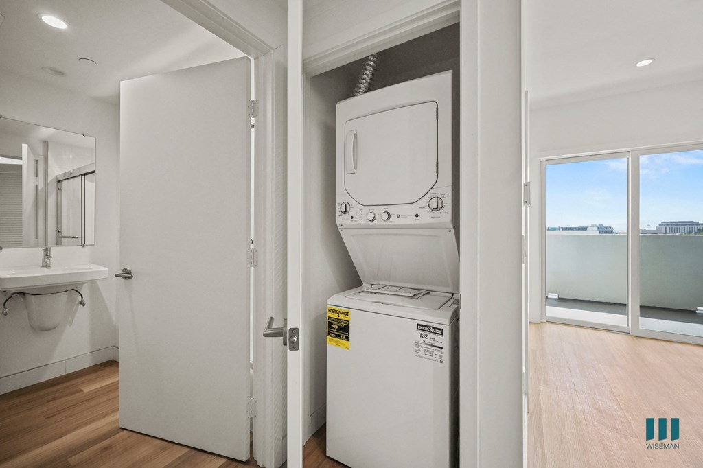 A white door is open to a bathroom with a washing machine in the other room.