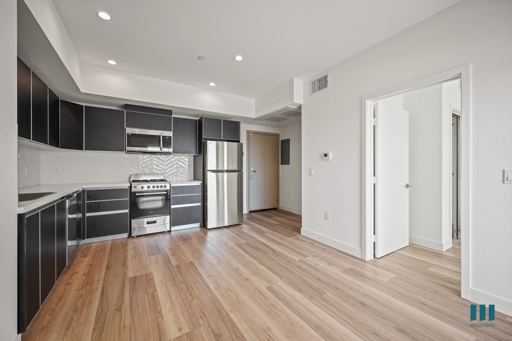 A modern kitchen with wooden floors and a white door.