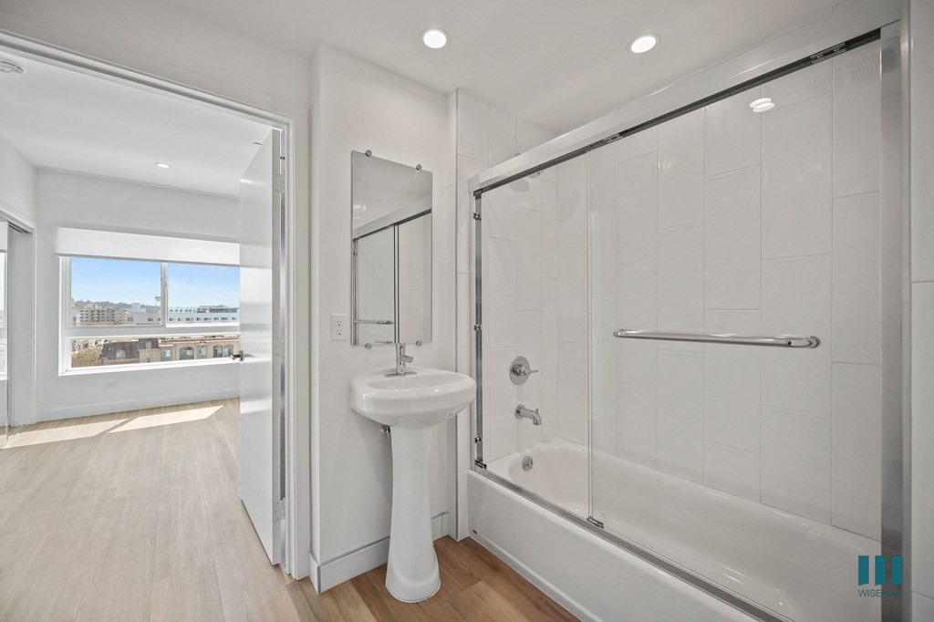 A white bathroom with a sink, mirror, and bathtub.