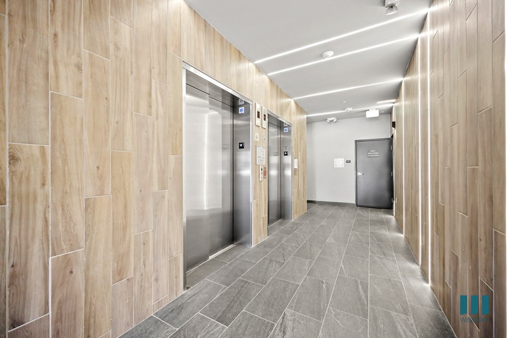 A long hallway with wood paneling and a metal elevator.
