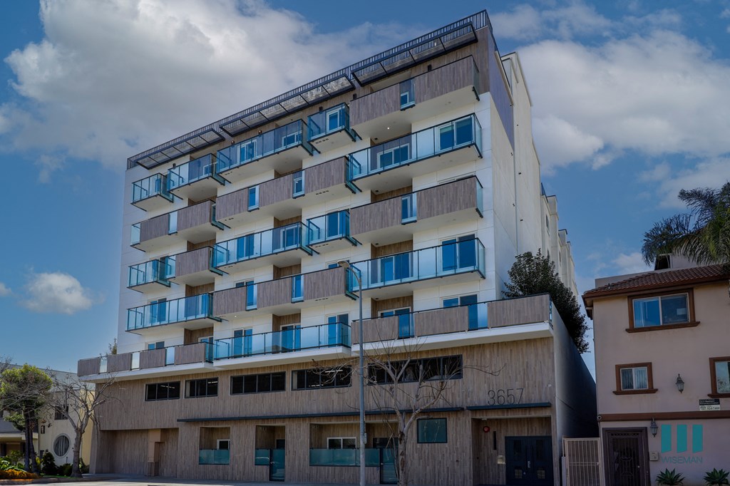 A tall building with balconies and a sign that reads "3657" on the front.