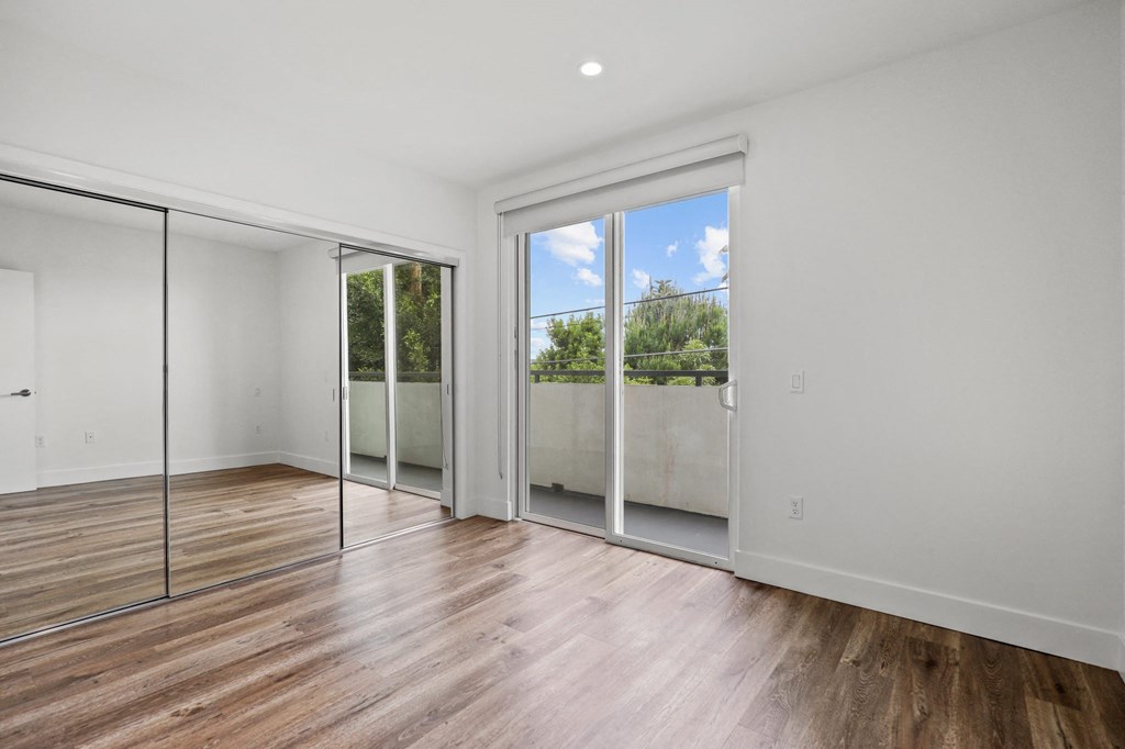 Bedroom with Mirrored Closet, Balcony, and Vinyl Flooring