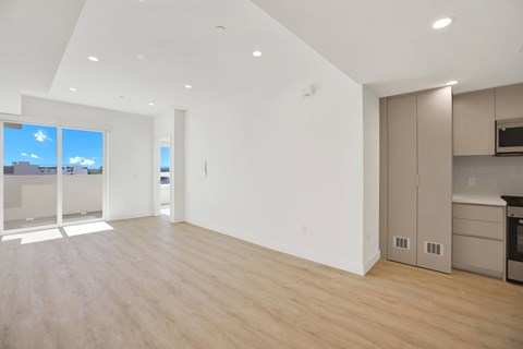 A spacious, empty room with wooden floors and white walls.