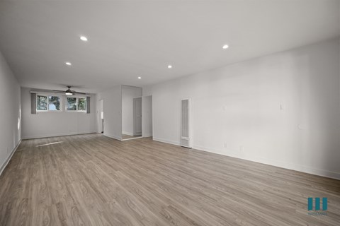 A spacious room with wooden flooring and white walls.