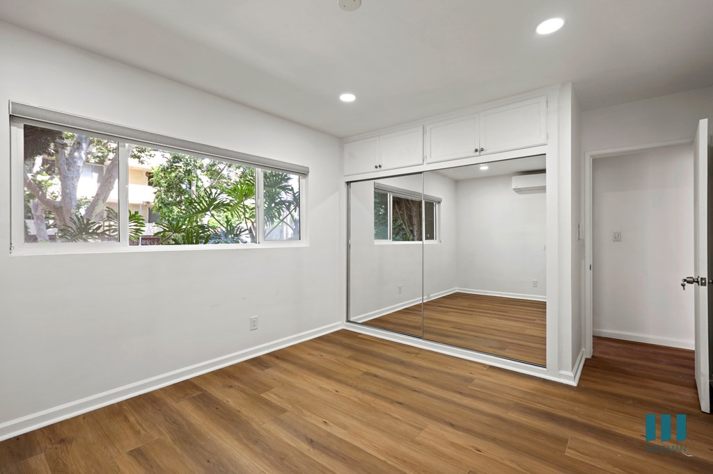 Bedroom with Windows, Mirrored Closet, Cabinet Storage, and Vinyl Flooring