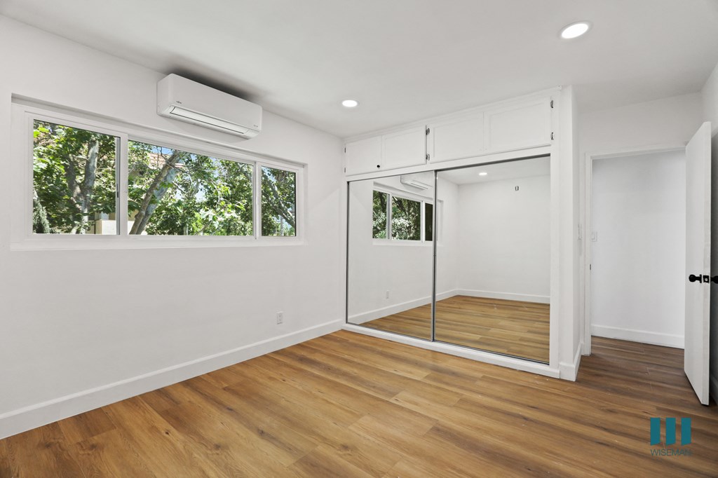 Bedroom with Mirrored Closet, Windows, and Vinyl Flooring