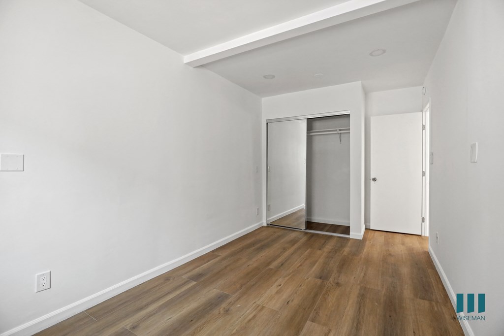 a bedroom with hardwood floors and white walls