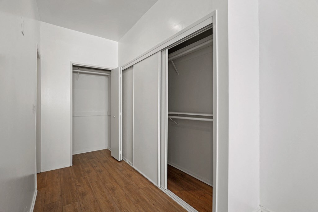 a bedroom with two closets and a hardwood floor