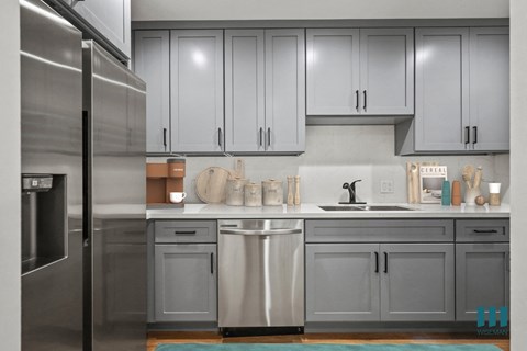 a kitchen with gray cabinets and stainless steel appliances