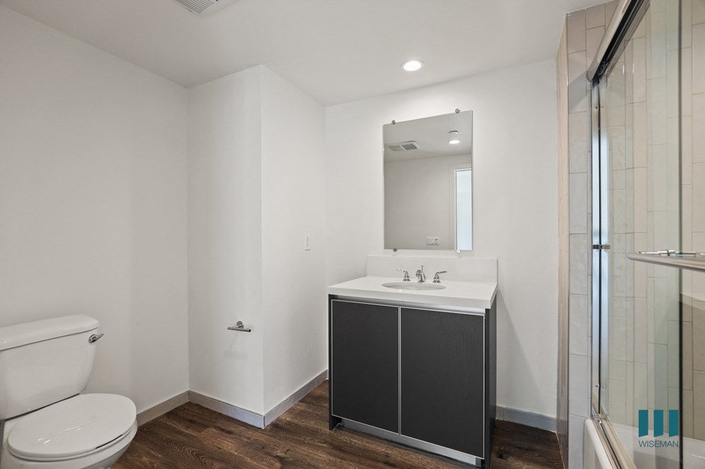 Bathroom with Full-Size Bathtub with Glass Door and Cabinet Storage