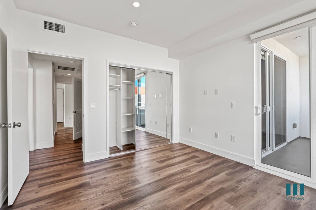 Bedroom with Patio Access and Mirrored Closet with Built-In Shelving