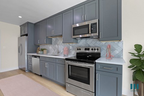 a kitchen with blue cabinets and a stove and a microwave