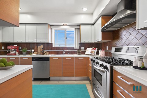 A modern kitchen with wooden cabinets and a stainless steel stove.