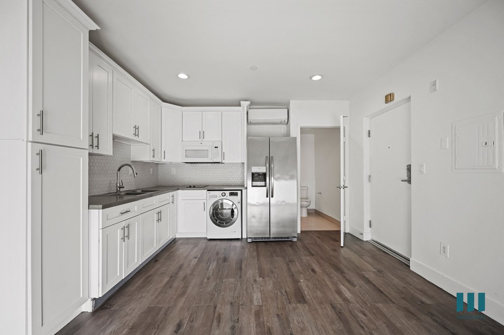 A kitchen with white cabinets and a washer and dryer in it.