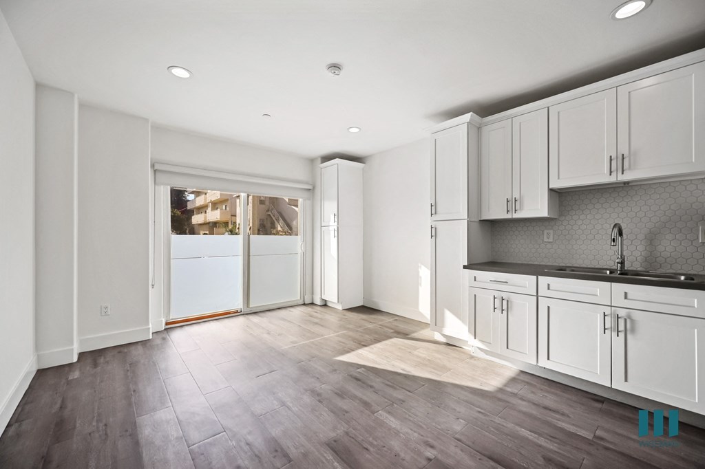 A kitchen with white cabinets and a grey backsplash.
