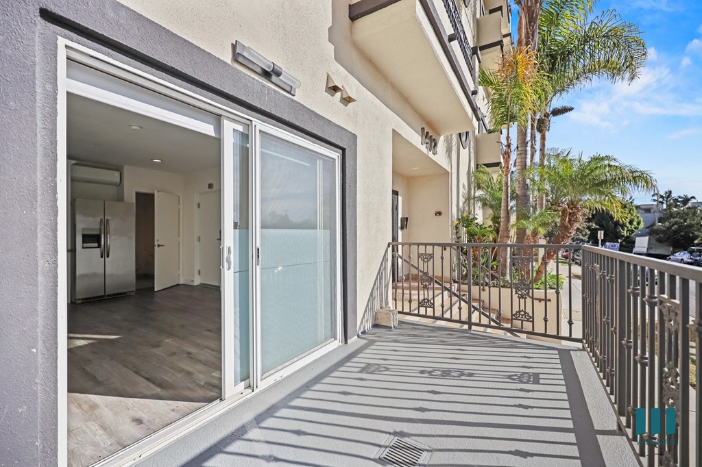 A balcony with a glass door leading to a kitchen.