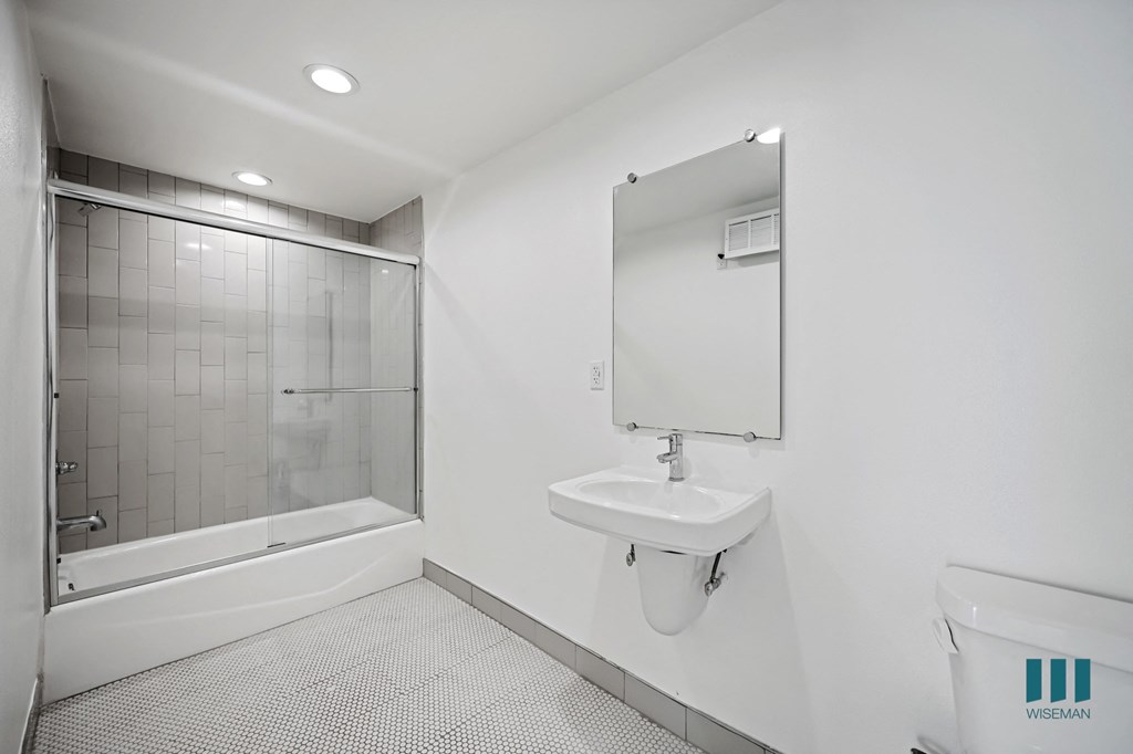 A bathroom with a white sink and a glass shower stall.