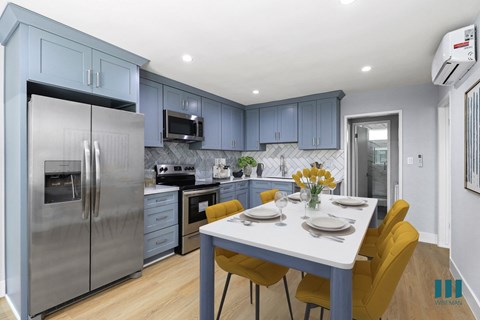 a kitchen with blue cabinets and stainless steel appliances and a table with yellow chairs