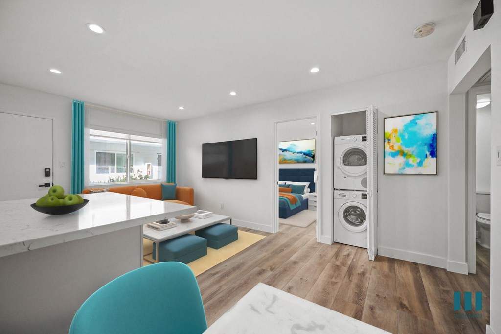 A modern kitchen with a blue chair and a bowl of green apples on the counter.
