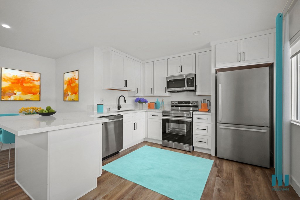 A modern kitchen with white cabinets and stainless steel appliances.
