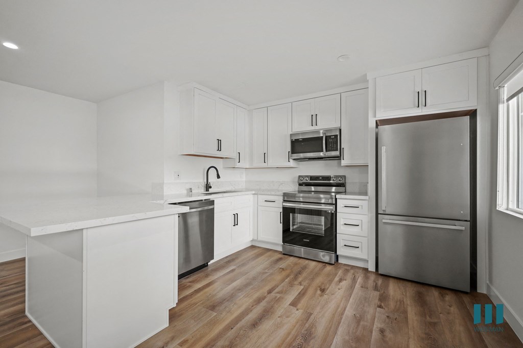 A modern kitchen with white cabinets and stainless steel appliances.