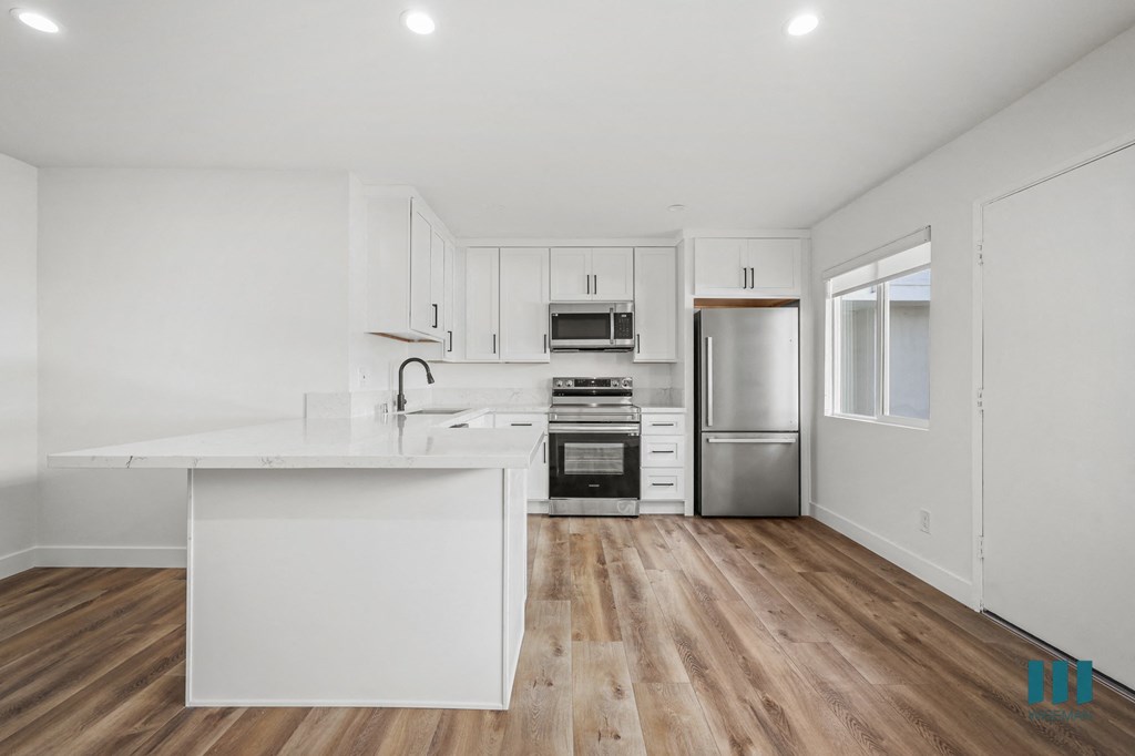 A kitchen with white cabinets and a wooden floor.