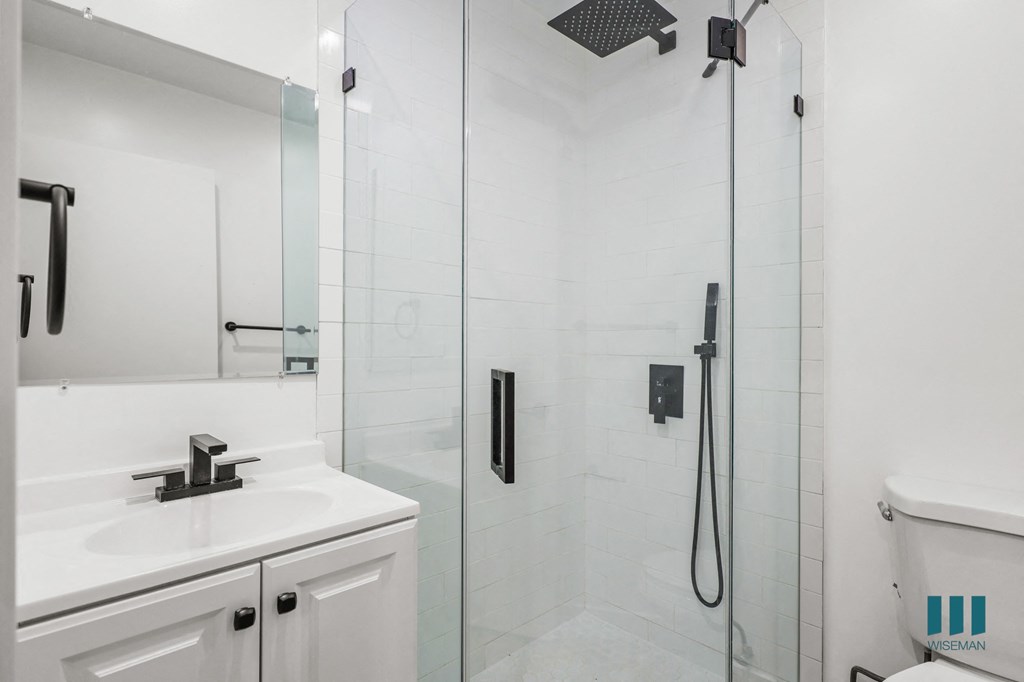 A white bathroom with a glass shower stall and a white tub.