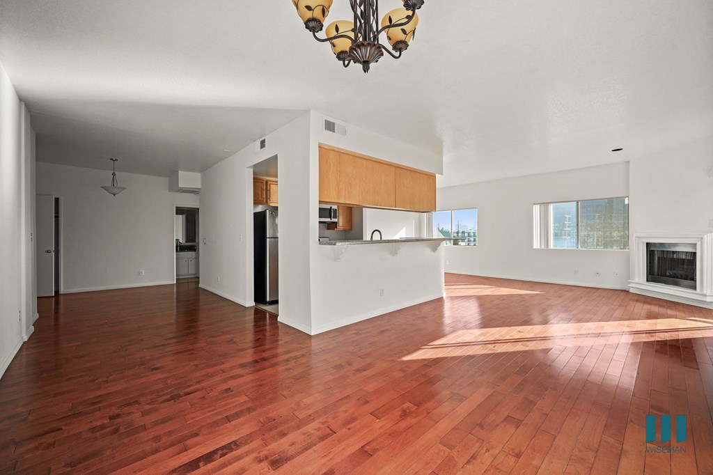 A large open room with wooden floors and a chandelier hanging from the ceiling.