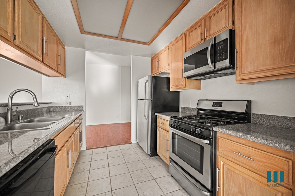 A kitchen with wooden cabinets and black appliances.