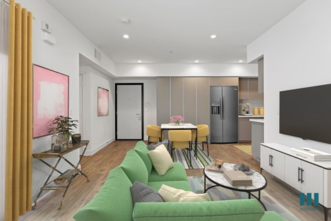 A living room with a green couch and a television on the wall.