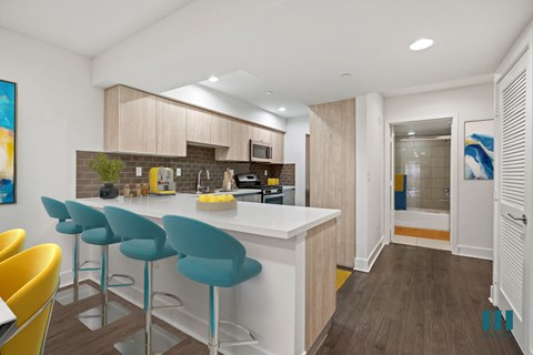 A kitchen with a white counter and blue bar stools.