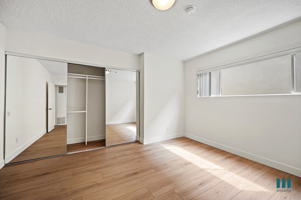 Bedroom with Vinyl Flooring and a Mirrored Closet