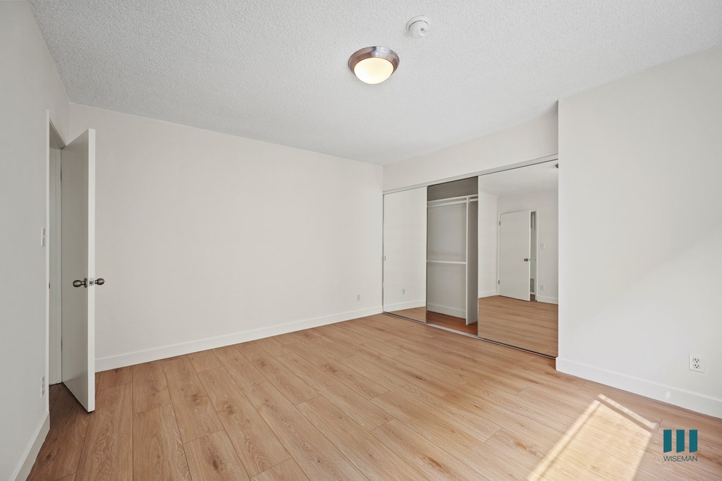 Bedroom with a Mirrored Closet and Vinyl Flooring