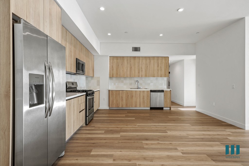 A modern kitchen with wooden cabinets and a stainless steel refrigerator.