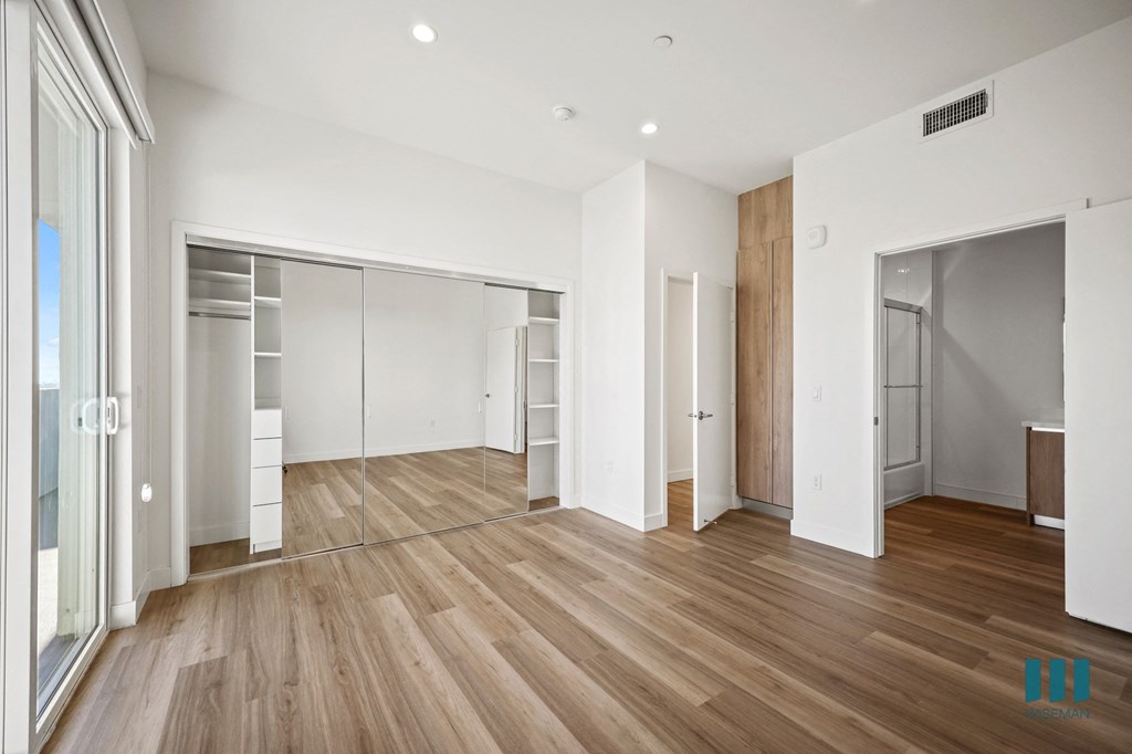 A spacious room with wooden flooring and white walls.
