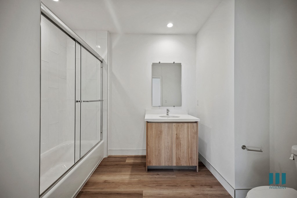 A modern bathroom with a wooden vanity and a walk-in shower.