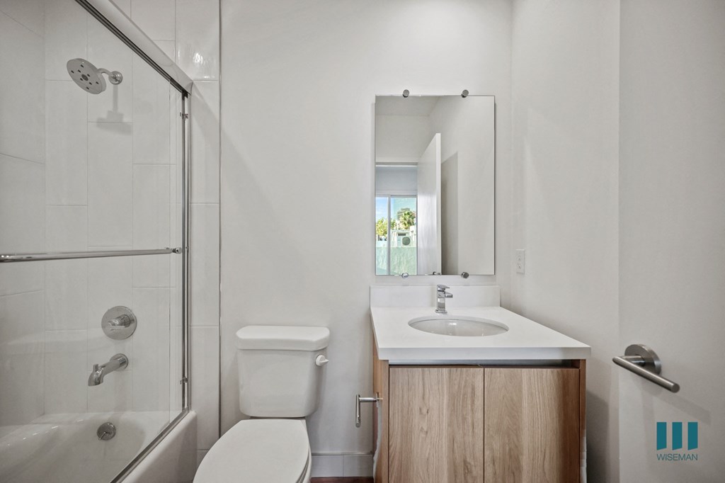 A bathroom with a white toilet, sink, and a glass shower stall.