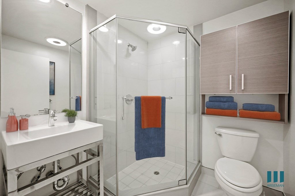 A bathroom with a white sink, a toilet, a shower with a glass door, and a mirror.
