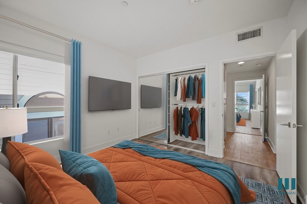 A bedroom with a bed covered in orange and blue comforters.